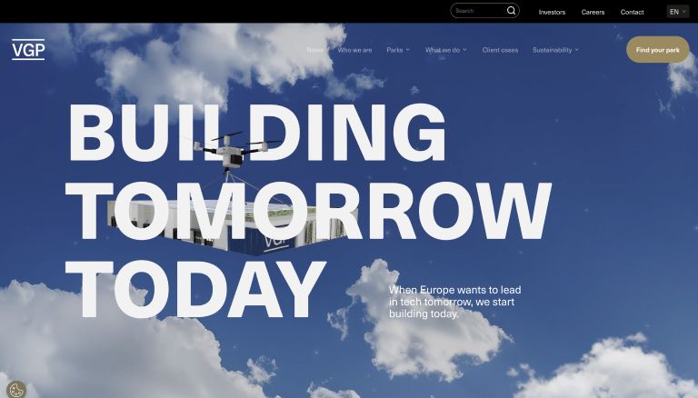 Drone draagt een modulair gebouw onder grote witte tekst "BUILDING TOMORROW TODAY" tegen blauwe lucht met wolken